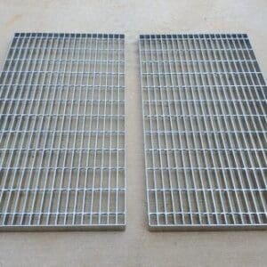 Two metal grates on a floor next to each other.