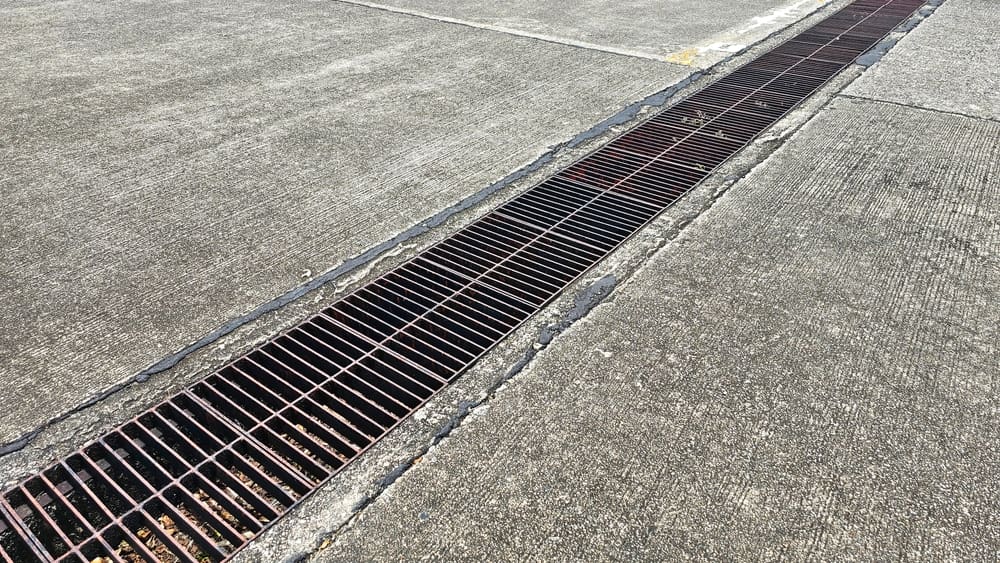 a metal drainage grate set in a concrete walkway