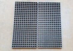 A pair of gray plastic grates sitting on top of a wall.