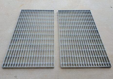 Two metal grates on a floor next to each other.